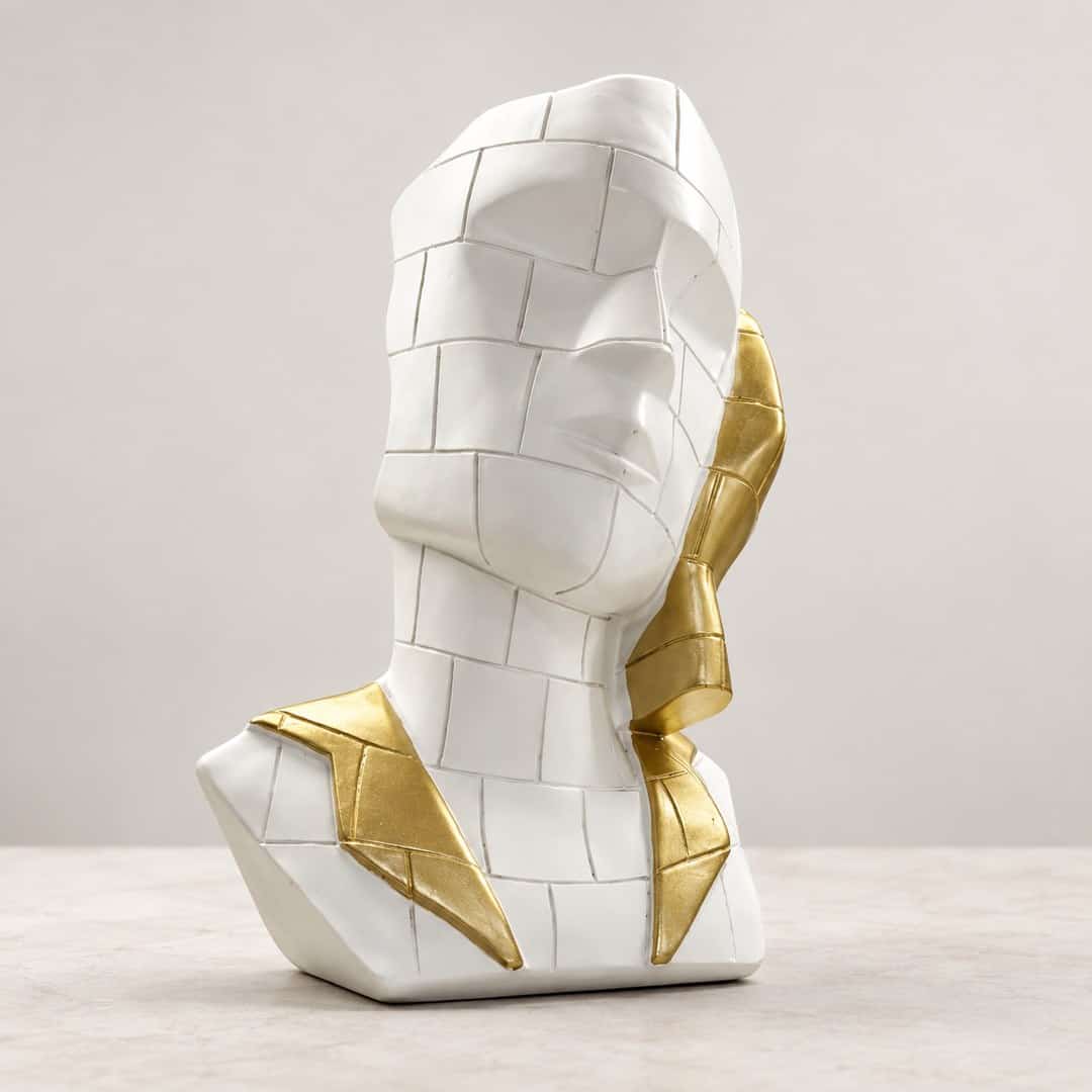 faceted white face sculpture with mosaic-style panels and a gold-tone side accent